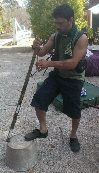 A photo of a man playing a small-sized washtub bass