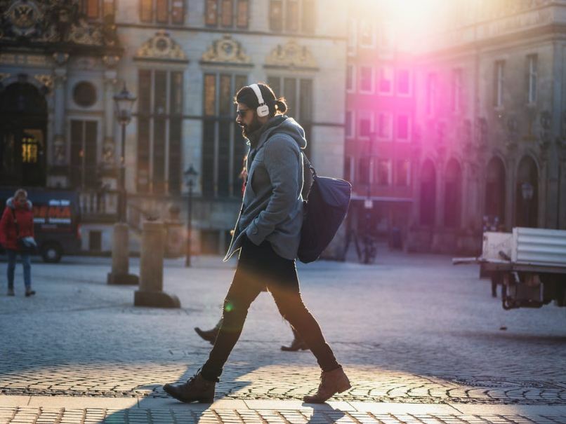 man-in-gray-hooded-jacket-walking-on-gray-bricks-pavement