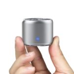 A small portable speaker held in fingertips