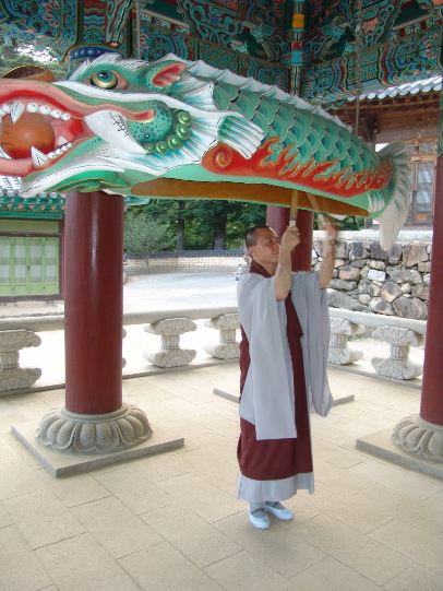 A photo of a monk playing the Korean wooden fish